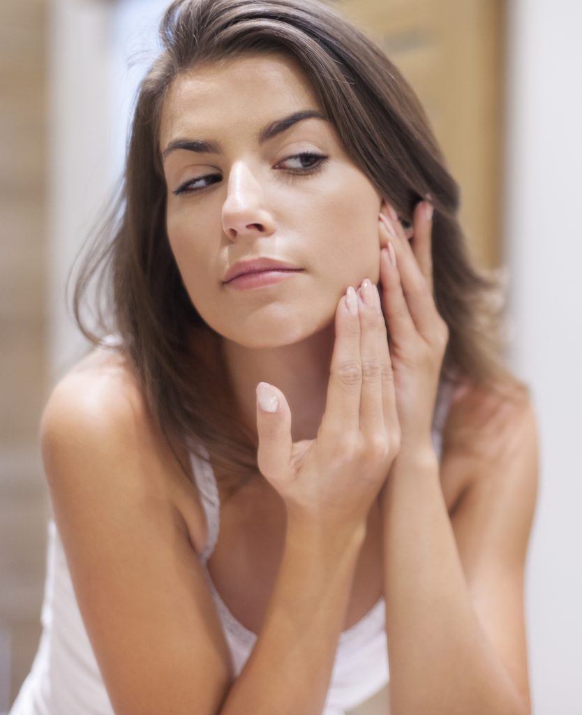 Brunette woman inspecting her face